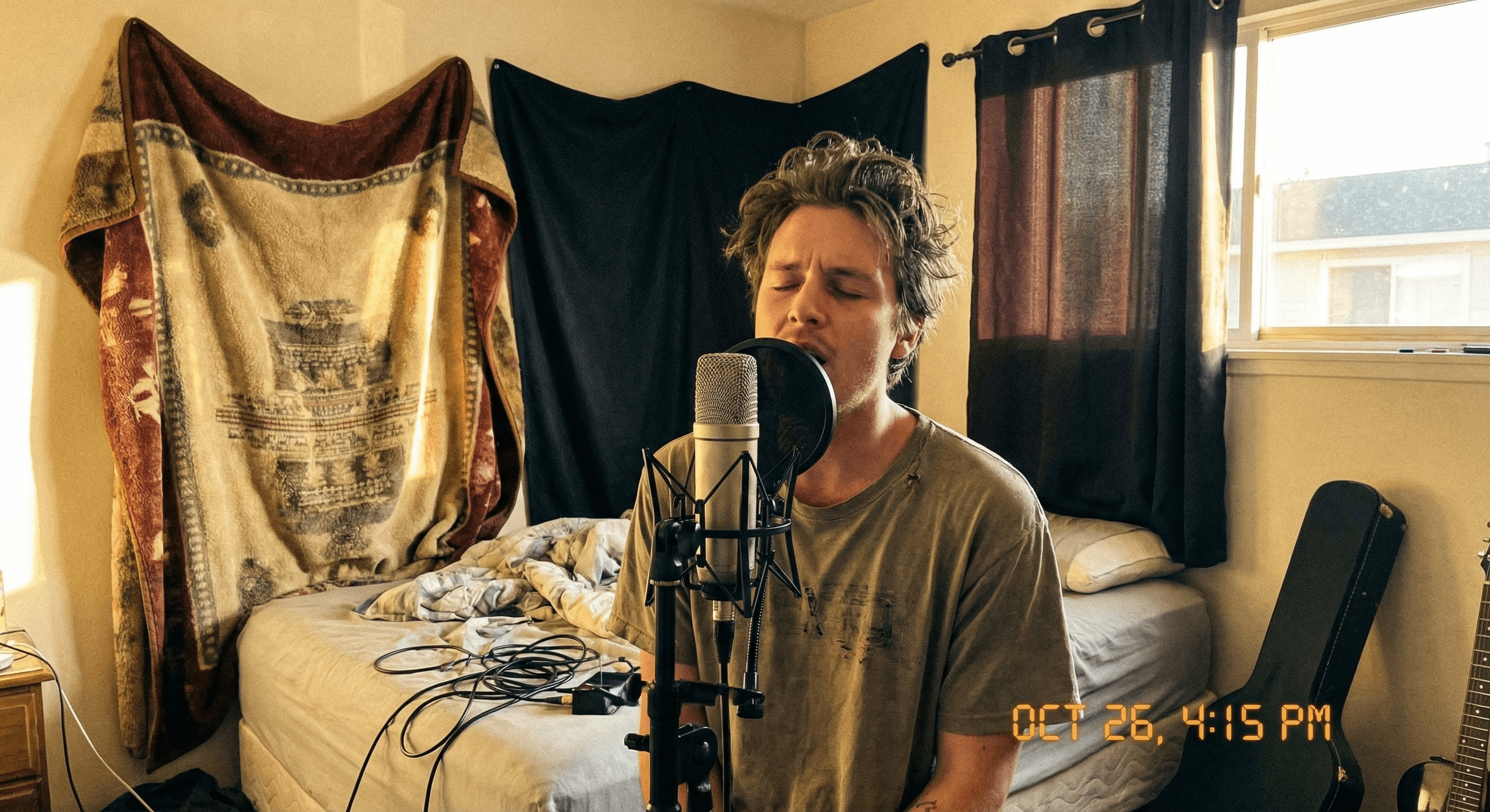 Singer recording vocals in a bedroom with DIY acoustic treatment